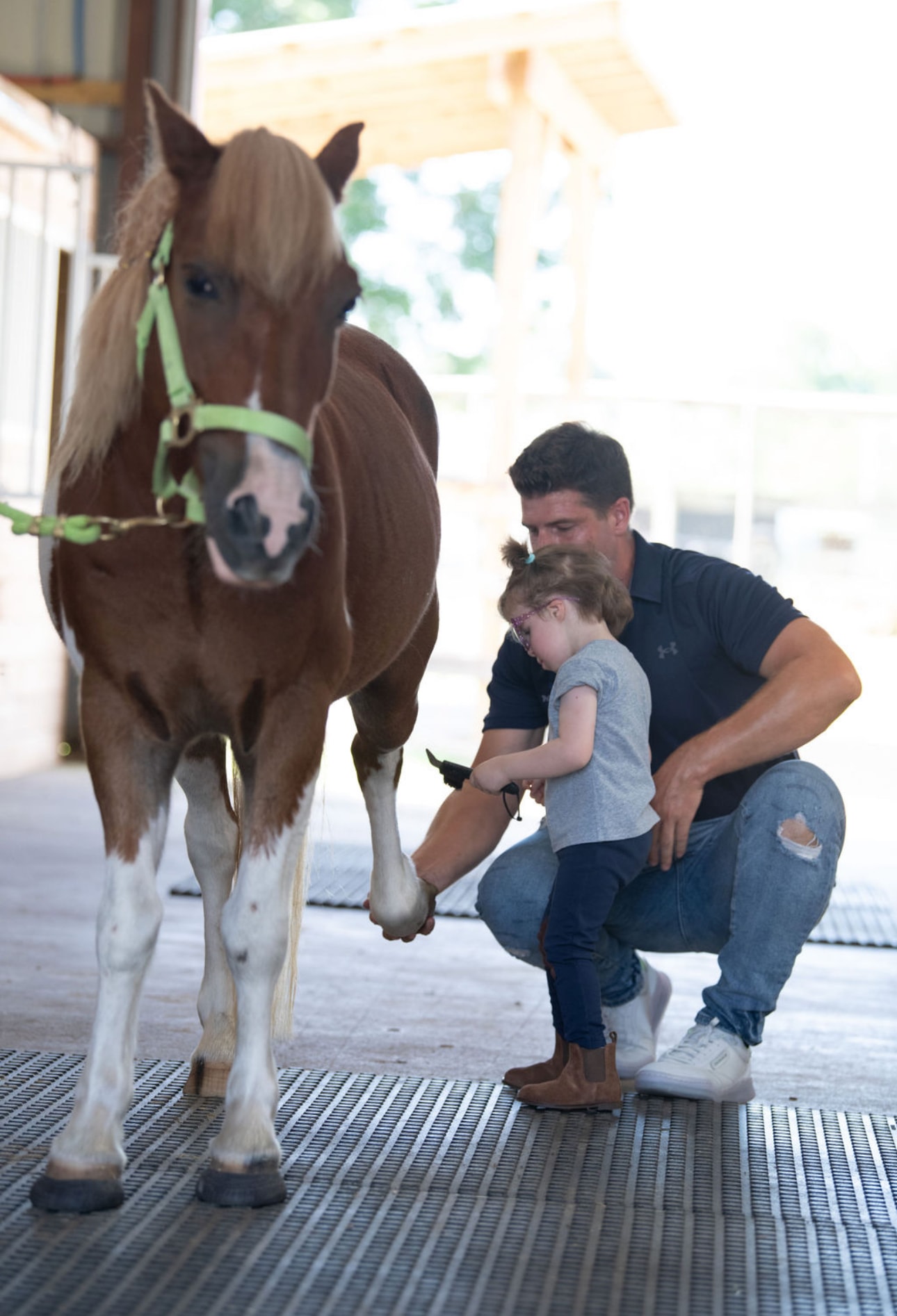 A young rider learning horse care with an instructor