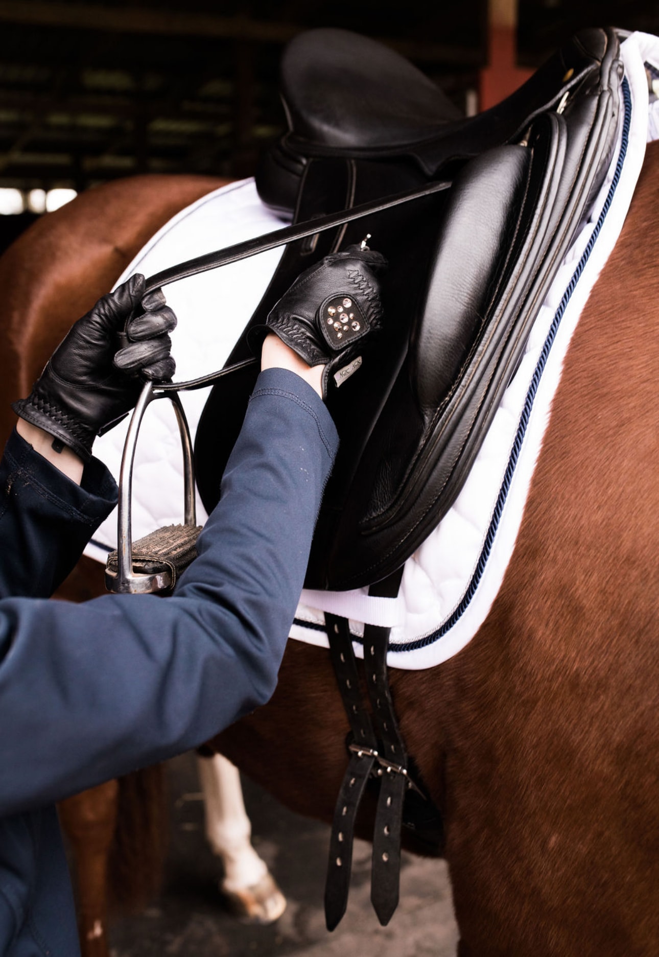 A rider preparing tack and adjusting the saddle