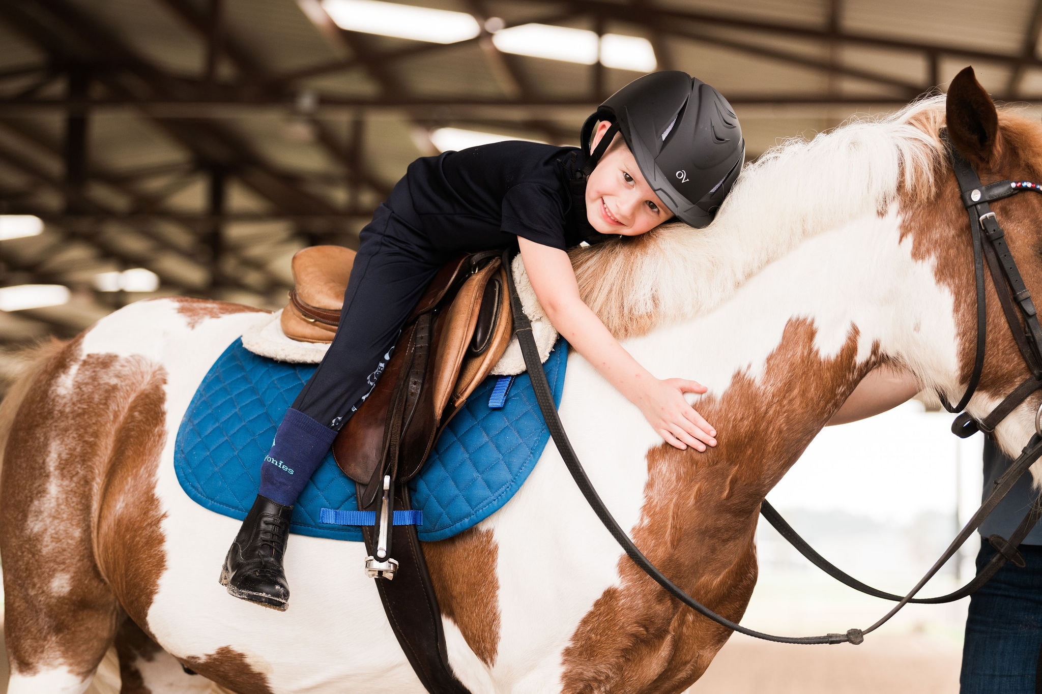 A young rider hugging a horse during a lesson in the Austin arena