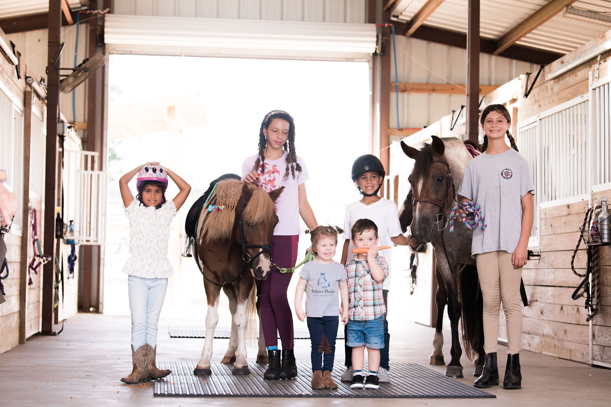 Young riders smiling with horses at the equestrian center